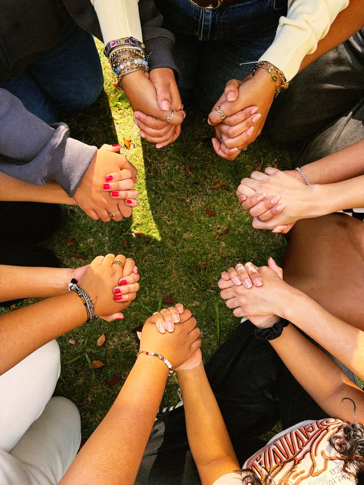 A circle of people holding hands in prayer on the grass